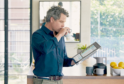 A man drinking coffee and read news on a 2-in-1